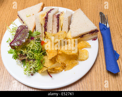 Lunchtime snack Cheddar cheese and chutney sandwich in white bread with mixed salad  potato crisps Stock Photo
