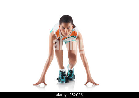 Portrait of young sporty woman at starting block of race isolated over white background Stock Photo