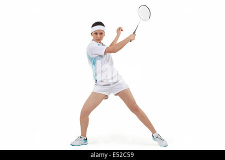 Young woman in sports wear playing badminton against white background Stock Photo