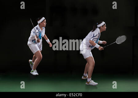 Profile shot of female players playing doubles badminton over black background Stock Photo