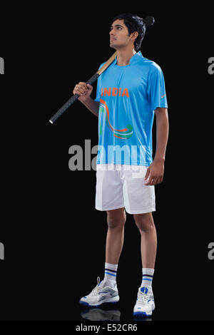 Full length of sportsman looking away while holding hockey stick over black background Stock Photo