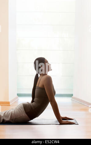 Young woman doing yogic 'sun salutation' on mat Stock Photo