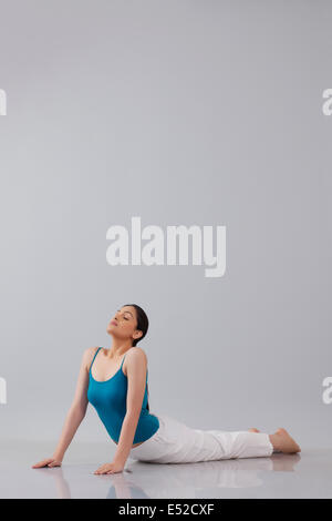 Young woman doing yogic 'sun salutation' isolated over gray background Stock Photo