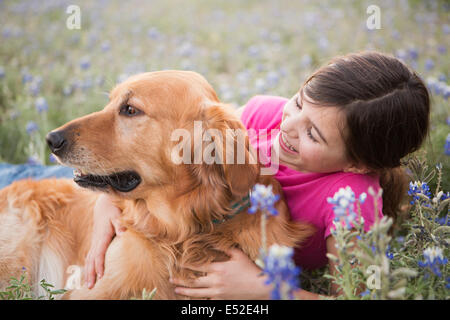 A young girl hugging a golden retriever pet. Stock Photo