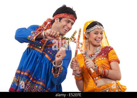 Happy young couple performing Dandiya Raas over white background Stock Photo