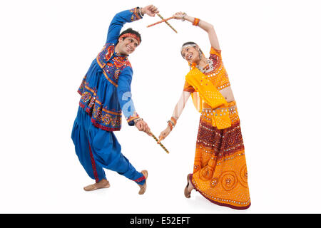 An Indian couple in traditional wear performing Dandiya Raas over white background Stock Photo