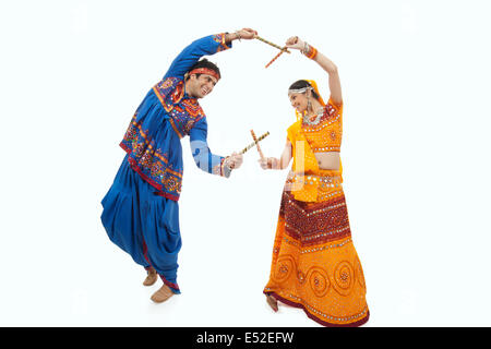 Young couple in traditional wear performing Dandiya Raas over white background Stock Photo