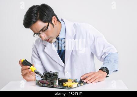Handsome technician working on computer part against gray background Stock Photo