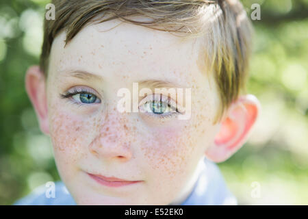 Portrait of a young boy with red hair, blue eyes and freckles on his nose. Stock Photo