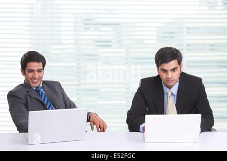 Businessmen using laptop at desk in office Stock Photo