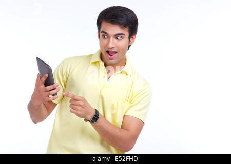 Surprised young man holding digital tablet isolated over white background Stock Photo