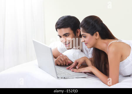 Happy young couple using laptop in bed Stock Photo
