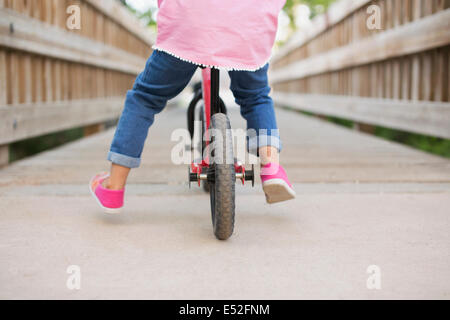 A child riding on a bicycle on a boardwalk.
