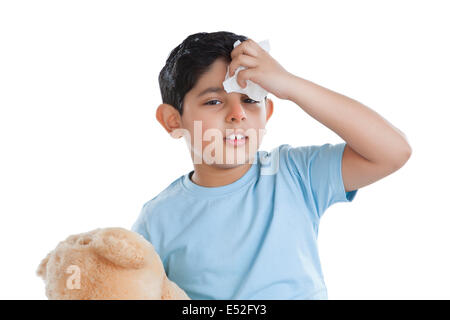Portrait of little boy putting ice on forehead Stock Photo