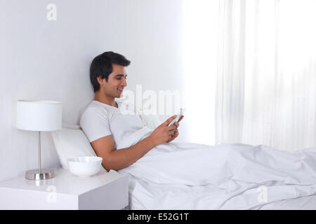 Relaxed young man using digital tablet in bed Stock Photo