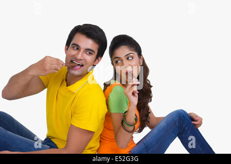 Young Indian couple enjoying ice-cream bars over white background Stock Photo