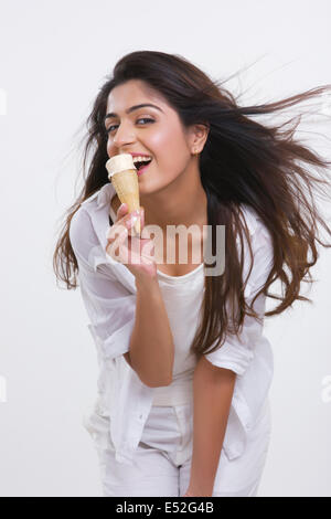 Portrait of happy young woman enjoying ice-cream cone isolated over white background Stock Photo