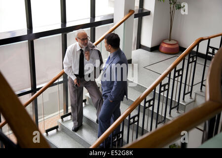 Two male executives talking on a staircase Stock Photo