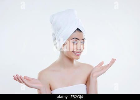 Portrait of young woman wrapped in towel gesturing against white background Stock Photo
