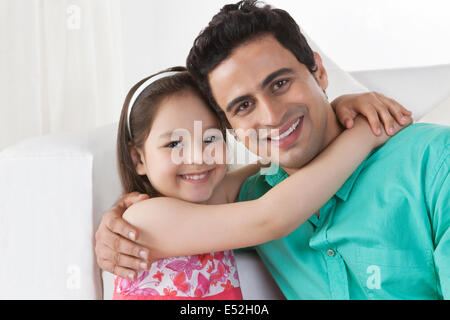 Portrait of happy girl embracing father in house Stock Photo