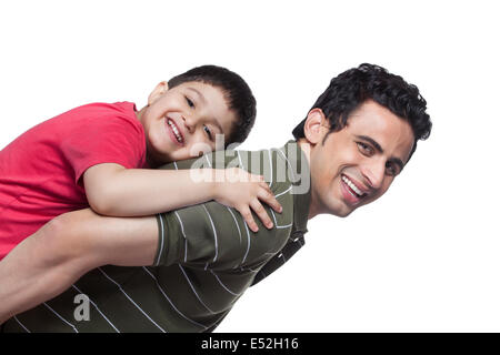 Portrait of happy father giving piggyback ride to son over white background Stock Photo