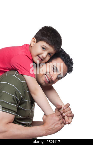 Portrait of father giving piggyback ride to son over white background Stock Photo