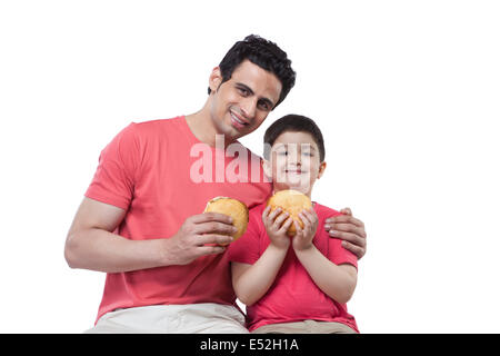 Portrait of happy father and son holding burgers over white background Stock Photo