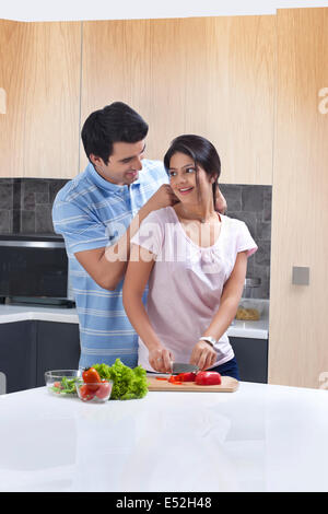 Man putting necklace on woman in kitchen Stock Photo