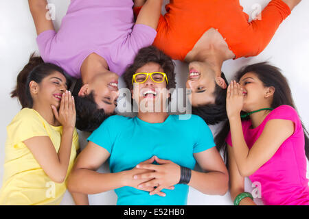 Directly above shot of friends sharing secret while lying on studio Stock Photo