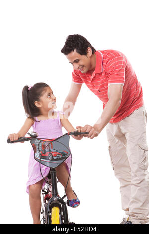 Happy father teaching daughter to ride bicycle against white background Stock Photo