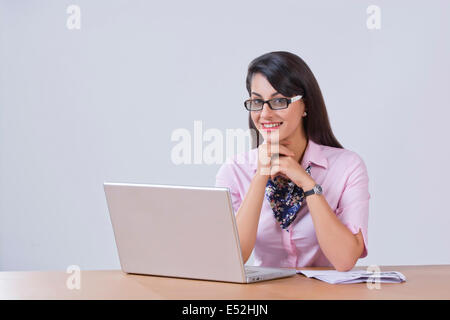 Portrait of happy businesswoman with laptop at office desk Stock Photo