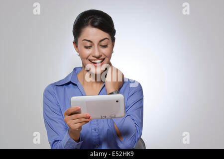 Happy Indian businesswoman using digital tablet against gray background Stock Photo