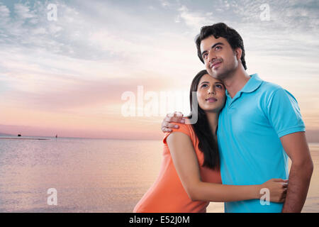 Thoughtful young couple embracing at beach Stock Photo
