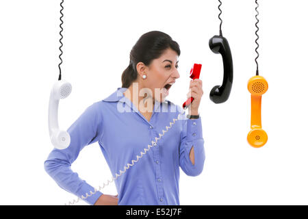 Frustrated businesswoman yelling into telephone receiver against white background Stock Photo
