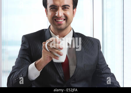 Portrait of happy businessman drinking coffee in office Stock Photo