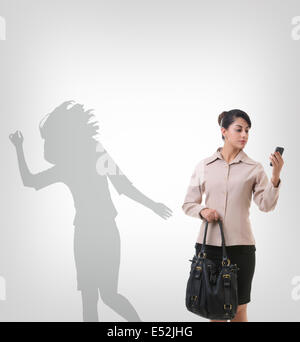 Businesswoman using mobile phone against shadow dancing over gray background Stock Photo