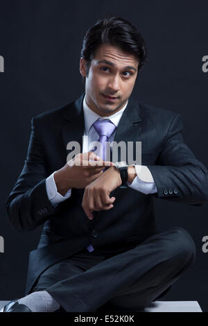 Young businessman checking time against black background Stock Photo