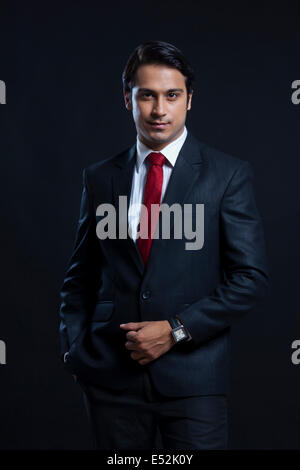 Portrait of confident businessman with hand in pocket over black background Stock Photo