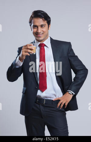 Smiling businessman drinking tea over gray background Stock Photo