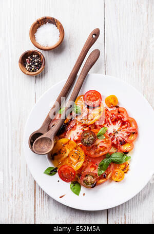 Ripe fresh colorful tomatoes salad with olive oil and balsamic vinegar on white wooden background Stock Photo