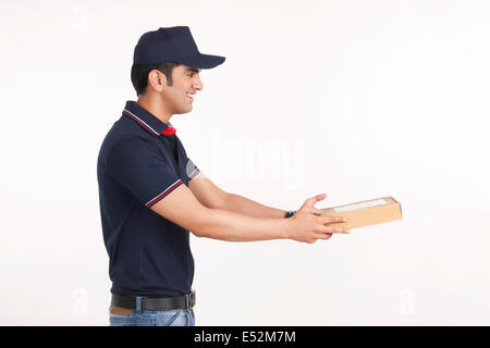 Side view of delivery man giving package against white background Stock Photo