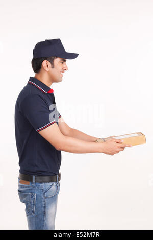 Profile shot of delivery man giving package against white background Stock Photo