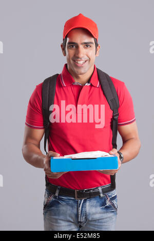 Portrait of smiling pizza delivery man against gray background Stock Photo