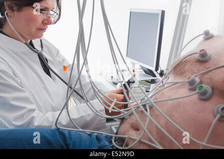 Cardiovascular stress testing-cardiologist checks blood pressure of overweight male patient Stock Photo