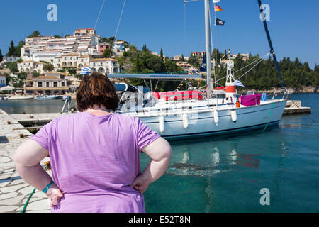 An obese woman next to her Yacht moored in the harbour in Sivota, Greece. Stock Photo