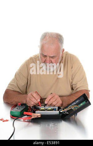 Closeup of a repairman using a voltmeter to test the components of an electrical device. The technician is looking down at his w Stock Photo