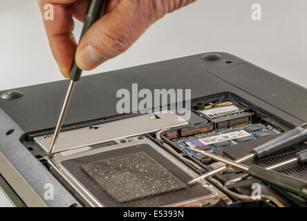 man fixing computer or laptop or notebook with crewdriver Stock Photo