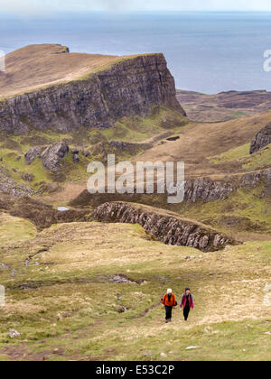 Two walkers on slopes of Meall na Suiramach with mountain crags near Flodigarry beyond, Trotternish, Isle of Skye, Scotland, UK Stock Photo