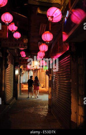 A couple of lovers walk hand in hand in a paved alley at dawn, under romantic lanterns in Jiufen (九份), Taiwan. Stock Photo