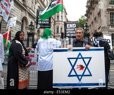 London, UK. 19th July, 2014. Artist, Kaya Mar, holds up his painting called 'Massacre of Innocence' as thousands of pro-Palestinian protesters gather outside No.10 Downing Street in London. The protesters are angered by the continued bombardment and ground offensives by the Israeli Defence Force in Gaza. Credit:  Pete Maclaine/Alamy Live News Stock Photo